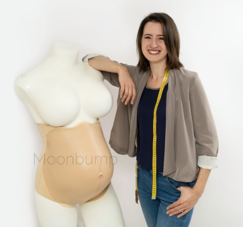 portrait of a woman standing next to a fake pregnant belly on a mannequin